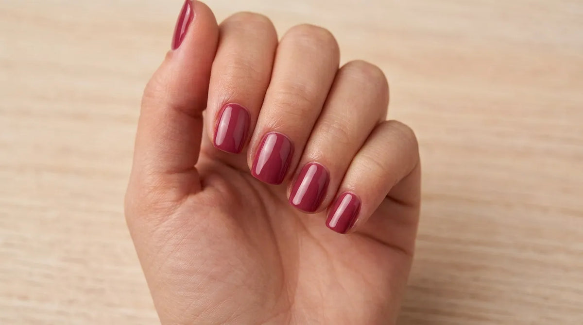 An exquisite manicure featuring deep rose-colored polish with a glossy, professional finish.